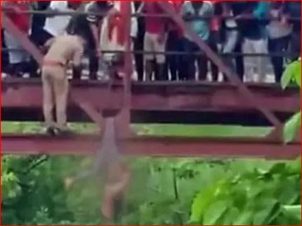 Seorang polisi negara bagian Uttar Pradesh, India, mengangkat jenazah gadis usia 17 tahun yang dibunuh keluarga dan mayatnya nyangkut kisi-kisi bawah jembatan. Foto: NDTV.com