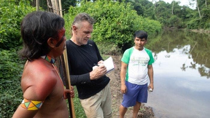 Jurnalis Dom Phillips (tengah) berbicara dengan dua pria pribumi di Aldeia Maloca Papiú, Negara Bagian Roraima, Brasil, pada 16 November 2019 (Foto:JOAO LAET/AFP)