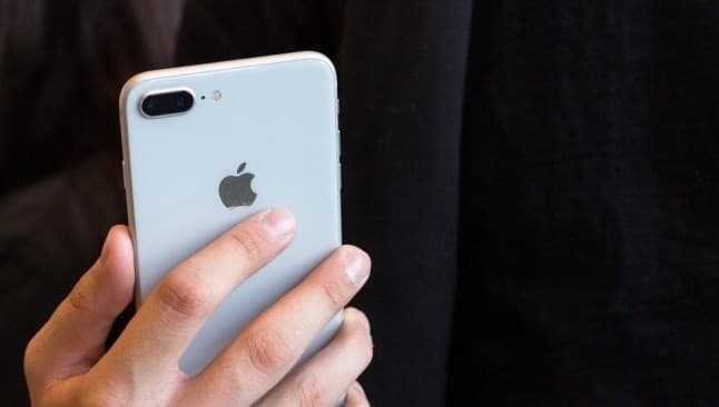Ilustrasi logo Apple di belakang iPhone