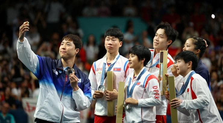 Lim Jong-hoon (kiri), atlet Korsel peraih medali perunggu tenis meja, berswafoto bersama atlet Cina, Korsel, dan Korut di podium penyerahan medali Olimpiade Paris 30 Juli. Foto: Yonhap