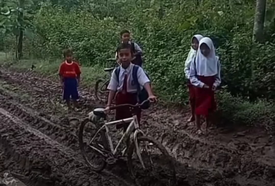 Anak-anak SD di Nganjuk, Jawa Timur melintasi jalanan rusak dan berlumpur menuju ke sekolah (Foto: Istimewa)